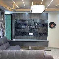 This drawing room features a bold TV unit with a dark stone-finish back panel and a floating grey console. The false ceiling with profile lights adds to the modern ambiance.