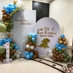 I bring beloved stories to life, like this "Lion King" theme for a first birthday party. The setup includes custom backdrops with "Hakuna Matata," a personalized circular sign, and balloon columns in jungle-inspired colors. The large light-up number '1' makes it clear this is for a milestone celebration.