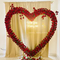 A close-up of our stunning red rose heart arch. The "Will You Marry Me" neon sign inside adds a modern touch and glows beautifully for evening proposals.