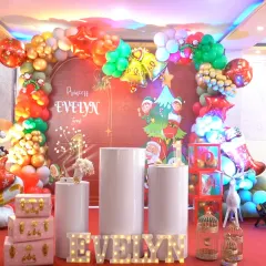 The full view of Princess Evelyn's Christmas-themed first birthday party, with red, green, and gold balloons.