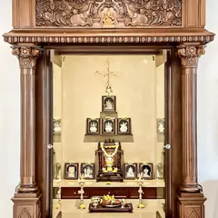 A traditional, temple-style pooja mandir crafted from dark wood. The ornate carvings, pillars, and glass doors make it a magnificent centerpiece for the home.