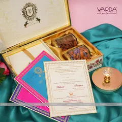 This stately invitation box features a custom family crest, exuding regal elegance. The interior is designed to hold both gourmet dry fruits and a complete set of vibrant, color-coded wedding ceremony cards.
