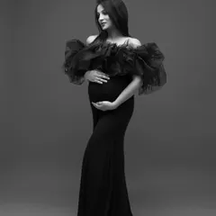 A solo portrait in black and white, emphasizing the elegant silhouette of the mom-to-be and the dramatic texture of her gown.