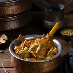 Nalli Nihari, a slow-cooked lamb shank curry, photographed for The Nawaab’s in Hyderabad. The dark, rustic styling complements the rich, traditional nature of this Hyderabadi specialty.