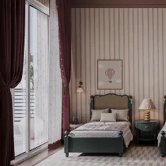 Heavy, deep red curtains frame a large window, adding a touch of drama and warmth to this shared bedroom. The natural light highlights the soft textures and gentle patterns used throughout the space, creating a cozy atmosphere.
