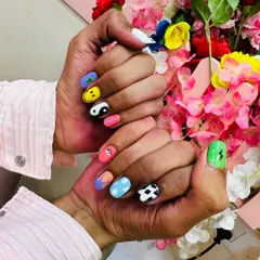 A fun and eclectic set of "random nail art," where each nail has a unique, hand-painted design including a smiley face, yin-yang, cow print, and more.