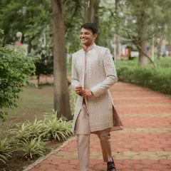 A happy, candid shot of the groom walking through a park, looking dapper in his white sherwani.