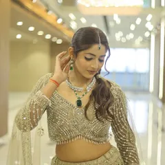 A beautiful party look featuring a shimmering gold lehenga. The makeup is kept soft and glowing, with emerald green jewellery adding a pop of colour. The focus is on radiant skin and defined eyes.