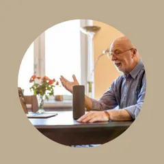 A senior comfortably uses a smart speaker, showcasing how natural and easy voice control can be for daily communication and home management.