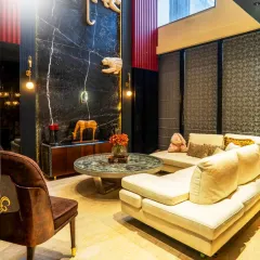 A wider view of the living area, showing how the dramatic double-height wall with black marble and hand-carved tigers serves as a stunning backdrop. The space is balanced with a comfortable L-shaped sofa and a unique center table, blending bold art with functional comfort.