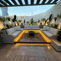 We designed this modern rooftop lounge with a custom sunken seating area to create an intimate and luxurious space for entertaining. The design features integrated perimeter lighting under the U-shaped sofa and strategically placed uplighting on tropical plants to enhance the evening ambiance.