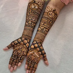 This engagement mehendi is both intricate and personal. It features the couple's initials "UV" and intertwined engagement rings, surrounded by beautiful peacocks, lotuses, and traditional patterns.