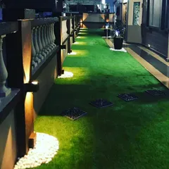 A long terrace walkway at night, featuring artificial grass, inset stepping stones, and uplighting. This shows how I can combine different materials to create a functional and beautiful path.