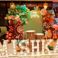 A full view of our Masha and the Bear themed stage. This setup includes life-size cutouts of both characters, a balloon tree, a neon sign, and large marquee letters, creating a perfect backdrop for cake cutting.