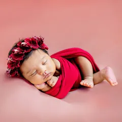 This little one looks like a beautiful rose, wrapped in red with a delicate floral crown. I use a variety of colorful wraps and props to style your newborn session.