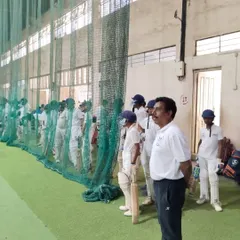 A coach keenly observes a young batsman during net practice at the trials. Every player gets a fair opportunity to show their skills.