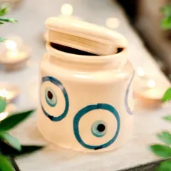 This ceramic jar with a hand-painted evil eye design is both charming and useful. It can be used to store trinkets or as a decorative piece, bringing a touch of protection and artistry to any space.