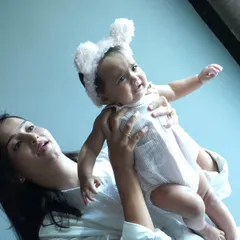 A mother lifts her baby up in a playful moment. We aim to capture these dynamic and loving interactions that show the unique personality of your family.