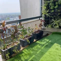A high-rise balcony makeover featuring artificial turf, a compact vertical garden, and a row of planters. This project shows how even small spaces can be maximized to include a variety of greenery, creating a private urban jungle.