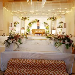 This behind-the-scenes photo shows the scale of a wedding reception stage I was setting up in a hall. The design features a floral arch over the main sofa and multiple floral arrangements on pedestals.