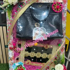 A beautiful multi-item hamper for Teej, including a handbag, a decorated clutch, and other traditional items, all arranged in a festive tray.