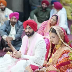 A candid moment during the Anand Karaj. The couple is seated, listening to the prayers, surrounded by their family. It's a photo filled with peace and devotion.