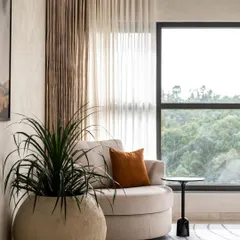 Warm minimalism envelops this understated master bedroom. We added a cozy corner hug chair to take advantage of the gorgeous forest view, creating the perfect Sunday vibe.