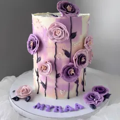 A beautiful cake in shades of purple. This tall cake features a watercolor effect and is adorned with handcrafted purple sugar flowers.