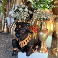 A close-up of a Nandi statue, a sacred and traditional element, decorated with a tilak and placed among golden vases, adding a touch of divinity to the decor.