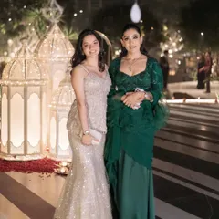 A mother-daughter duo in custom fusion wear. The daughter wears the pearl and sequin peplum top with a patterned skirt, while I wear a hand-embroidered blouse with a satin skirt and georgette organza drape.