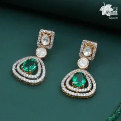 A close-up of the Green Grace earrings. Notice the double halo of diamonds surrounding the central emerald, and the elegant Polki diamonds that connect the drops, showcasing fine, detailed craftsmanship.