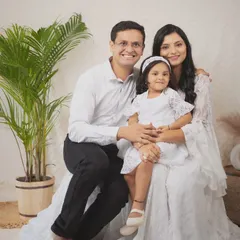 A picture of a happy family. Dressed in coordinating white outfits against a bright, boho-inspired backdrop, their smiles radiate warmth and love. This is what a perfect family portrait feels like.