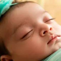 A macro shot of a sleeping newborn's face, highlighting the delicate details of their eyelashes and lips.