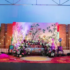 A wider view of the artistic Mehendi stage setup, showing the full context with the brick wall and stage flooring. The mix of colors and textures creates a wonderful atmosphere.
