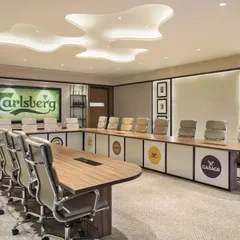 The boardroom at the Carlsberg office, where brand identity is woven into every detail. The custom table features logos of Carlsberg's various brands, while the back wall displays historic memorabilia, creating a space steeped in corporate heritage.