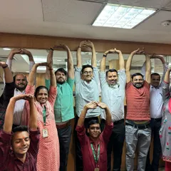 A happy group of employees at SMC Global making a heart shape with their arms. These sessions are not just about yoga; they are about team bonding and boosting morale.