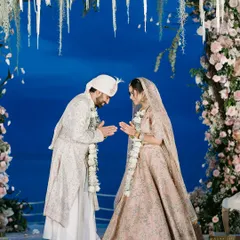 A serene moment between the couple at their beachside mandap in Thailand, set against a stunning blue backdrop and floral arch.