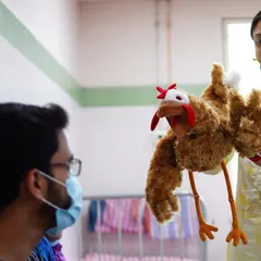 A chicken puppet has a conversation with a doctor. These playful interactions help humanize the hospital experience and create positive memories for everyone involved.