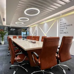 The main boardroom at Rays Power, designed for executive meetings. The space features a large marble-topped table, comfortable leather chairs, and modern ring lighting, with a motivational quote on the wall to inspire teamwork.