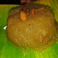 A serving of our soft and fragrant Pineapple Kesari Bath. This sweet semolina dish is enriched with ghee, sugar, and pieces of fresh pineapple, then garnished with nuts for a delightful taste.