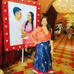 Posing by a photo of the happy couple, Kalp and Dishani, at their Mayera and Sangeet function. I love adding personal touches like these photo displays that celebrate the couple's journey as I host their pre-wedding events.