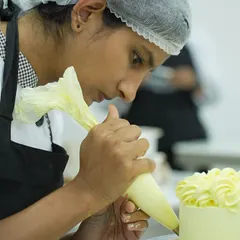 Here, I am guiding a student as she perfects her piping technique. In my class, you get complete hands-on practice, and I am right there to help you master the skills needed for professional cake and cupcake decoration.
