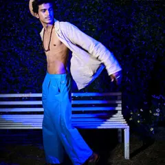 Capturing the energy of a runway show with dramatic, stylized blue lighting. This shot freezes the model in motion, highlighting the flow of the designer's garment in a high-energy, editorial context.