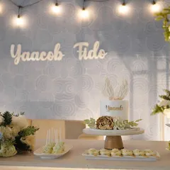 An elegant dessert table for a baptism ceremony. The setup includes a custom cake, cupcakes, and other small treats, all coordinated with the event's theme and color scheme.