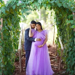 A tender moment between parents-to-be. This lavender tulle gown adds a touch of fairytale romance to this maternity shoot, framed beautifully by a natural green archway.