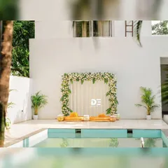 This minimalist poolside Haldi decor offers a modern and chic alternative. A simple floral frame of white roses and green leaves creates an elegant backdrop for the ceremony, perfectly complementing the serene setting.