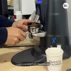 A student practices grinding beans for an espresso shot. Our flagship program provides extensive hands-on time with professional-grade equipment to build muscle memory and confidence.