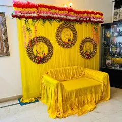 Another perspective of the haldi decoration setup inside a client's home. The bright colors and floral elements create a festive atmosphere for your pre-wedding events.