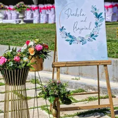 For Deeksha and Prajwal's outdoor event, we designed this watercolor-themed welcome sign placed on a rustic wooden easel. The sign was complemented by floral arrangements in modern metallic vases, blending artistry with nature.