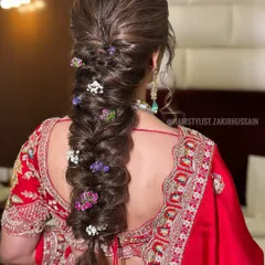 I created this voluminous fishtail braid and wove in small, colorful flowers for a fresh and vibrant look. This style is perfect for a Mehendi or a daytime wedding ceremony.